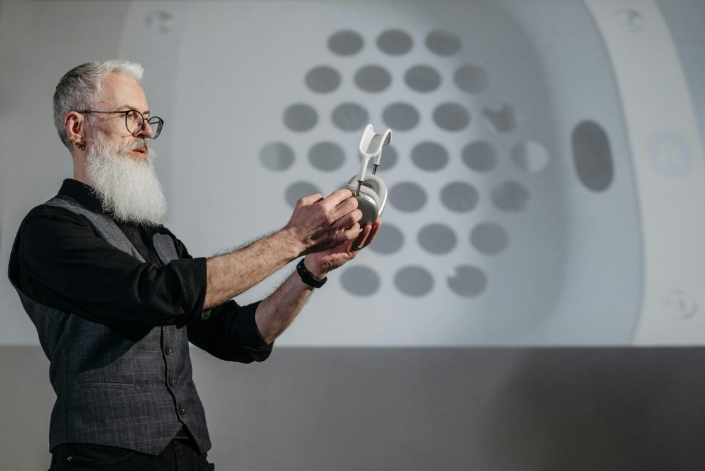 Senior man showcasing wireless headphones with a projected background. Perfect for business and tech concepts.